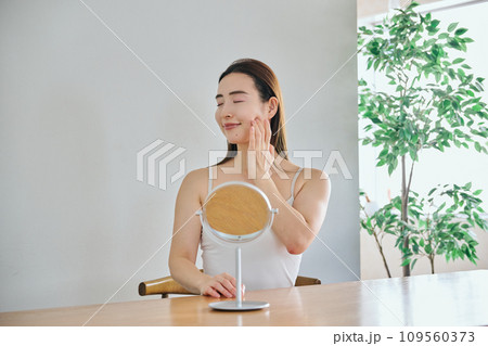 顔をマッサージして肌のお手入れをする30代女性 109560373