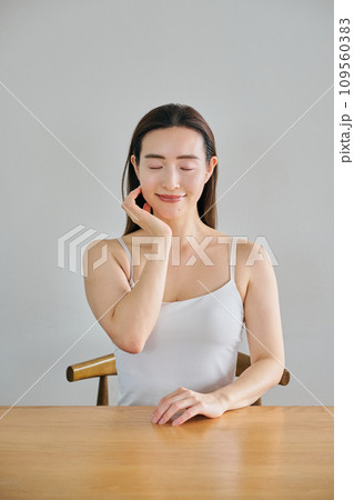 顔をマッサージして肌のお手入れをする30代女性 109560383