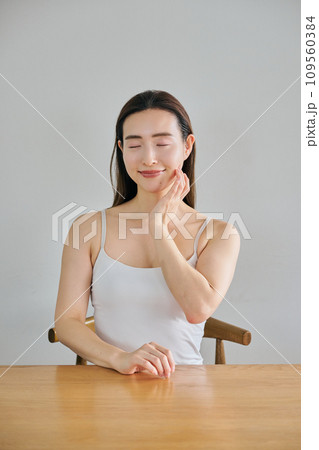 顔をマッサージして肌のお手入れをする30代女性 109560384