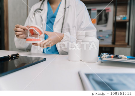 Dentist holding tooth model in the morning at the desk. Dentist holding tooth model in the morning at the desk. 109561313