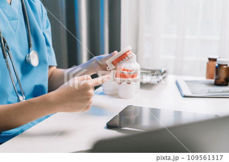 Dentist holding tooth model in the morning at the desk. Dentist holding tooth model in the morning at the desk. 109561317