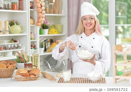Beautiful young woman in chefs hat baking at home 109561722
