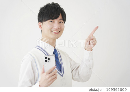 スマートフォンを持って右側を指差す男子高校生 白背景 スマートフォンを持って右側を指差す男子高校生 白背景 109563009