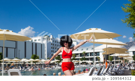 A woman performs sports exercises near the pool in a hotel A woman performs sports exercises near the pool in a hotel 109564312