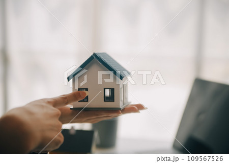 Real estate broker agent presenting and consult to customer to decision making sign insurance form agreement, buy and sell home model, concerning mortgage loan offer for and house insurance 109567526