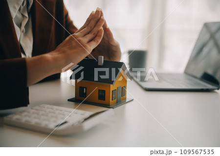 Real estate broker agent presenting and consult to customer to decision making sign insurance form agreement, buy and sell home model, concerning mortgage loan offer for and house insurance Real estate broker agent presenting and consult to customer to decision making sign insurance form agreement, buy and sell home model, concerning mortgage loan offer for and house insurance 109567535