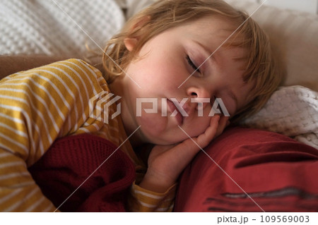 Peaceful adorable baby sleeping on a bed at home. Slumbering little child. Two year old girl sleeps peaceful at domestic room interior background. Serene dream. Cute face close up. Deep kid slumber Peaceful adorable baby sleeping on a bed at home. Slumbering little child. Two year old girl sleeps peaceful at domestic room interior background. Serene dream. Cute face close up. Deep kid slumber 109569003