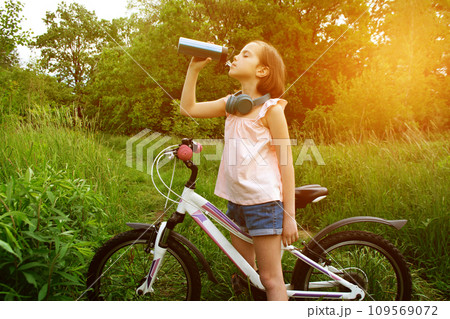 Little cute girl riding a bike with basket full of flowers. 109569072