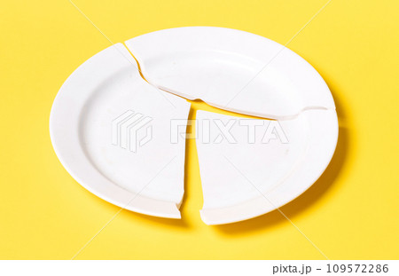 Broken white plate on a solid background Broken white plate on a solid background 109572286