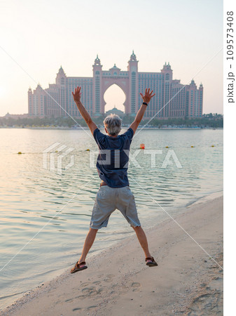 Senior visiting Palm Jumeirah in Dubai standing on the public beach Senior visiting Palm Jumeirah in Dubai standing on the public beach 109573408