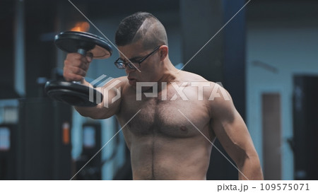Muscular arab man training with dumbbells in the gym. Muscular arab man training with dumbbells in the gym. 109575071
