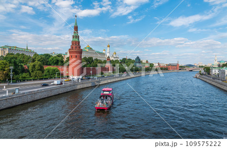 View of Kremlin with Vodovzvodnaya tower, Grand Kremlin Palace from repaired Bolshoy Kamenny Bridge in Moscow city on sunny summer day. Cruise ship sails on the Moscow river 109575222