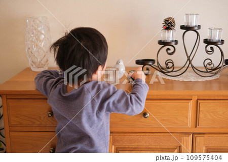 4歳の男の子がリビングボードの飾り物に興味をもつ。 4歳の男の子がリビングボードの飾り物に興味をもつ。 109575404