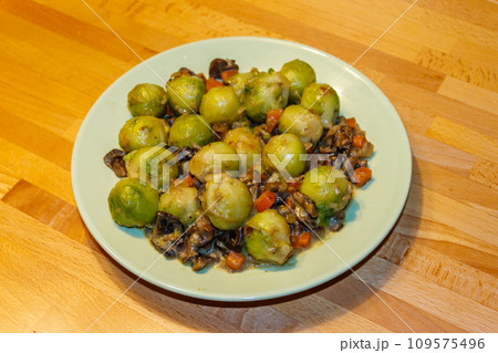 Brussels sprouts roasted with mushrooms and carrot on wooden table 109575496