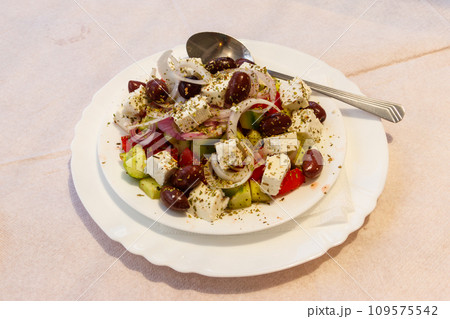 Greek salad with fresh vegetables, feta cheese and olives on a table Greek salad with fresh vegetables, feta cheese and olives on a table 109575542