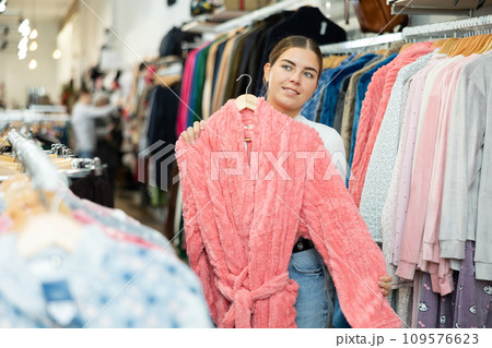 Young woman choosing bathrobe in store Young woman choosing bathrobe in store 109576623