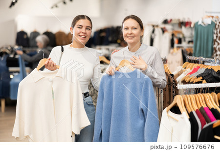 Young and adult women choosing coat in store Young and adult women choosing coat in store 109576676