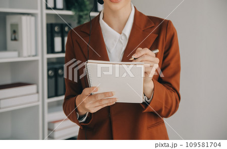 Beautiful female call center operator working on computer in office Beautiful female call center operator working on computer in office 109581704