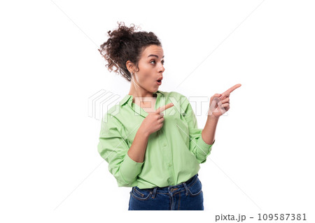 young brunette curly slender female model dressed in a light green shirt points with her hand at the young brunette curly slender female model dressed in a light green shirt points with her hand at the 109587381
