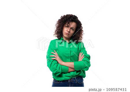serious young woman with black curly hair dressed in a green shirt on a white background serious young woman with black curly hair dressed in a green shirt on a white background 109587431