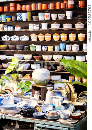 Small store with many pottery ceramic standing on shelves. 109587705
