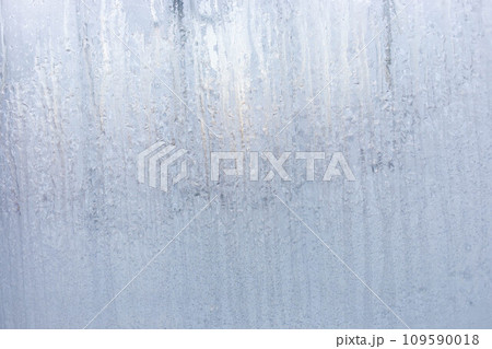 Winter window with frozen vertical water stripes. Frosty patterns on winter iced white window glass 109590018