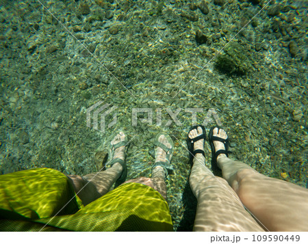 Feet Submerged in Clear Shallow Waters Over Riverbed Feet Submerged in Clear Shallow Waters Over Riverbed 109590449