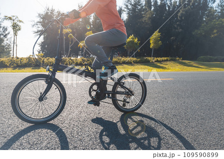 Riding folding bike on sunny seaside road Riding folding bike on sunny seaside road 109590899