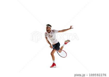 Concentered young man, tennis payer in motion during game, training, hitting ball with racket isolated over white background. Sport 109592276