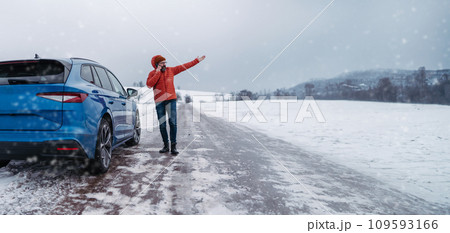 Angry man standing by electric car, battery run out of power before reaching destination. Man phone calling for help, waiting for breakdown service car, tow truck. Banner with copy space. 109593166