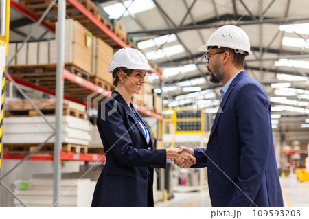 Female engineer and male project manager shaking hands in modern industrial factory. Manufacturing facility with robotics and automation. Women in manufacturing. Female engineer and male project manager shaking hands in modern industrial factory. Manufacturing facility with robotics and automation. Women in manufacturing. 109593203
