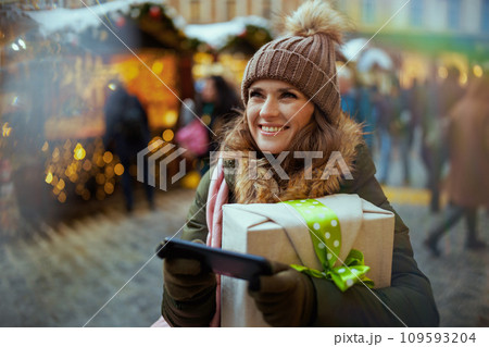 happy modern woman at christmas fair in city using smartphone 109593204