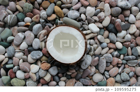 Half Coconut On A Colored Sea Stones Texture Background  109595275