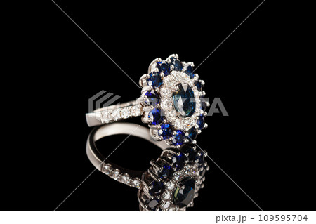 Beautiful ring with sapphires and diamonds in gold on a black background Beautiful ring with sapphires and diamonds in gold on a black background 109595704