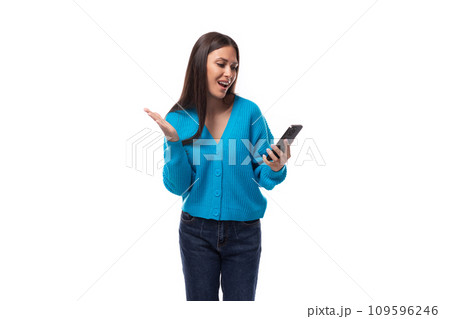 young brunette woman dressed in a blue sweater with buttons thinks what to answer on a message in a 109596246