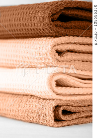Stack of colorful cotton kitchen towels toned with color of the year 2024 Peach Fuzz 109596350