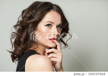 Pensive brunette woman face close up beauty fashion portrait. Lady with makeup and dark wavy hair 109597668