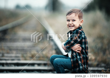 Lonely boy sits on railroad tracks. Mischievous man ran away from home. Bad boy. Lonely boy sits on railroad tracks. Mischievous man ran away from home. Bad boy. 109597930