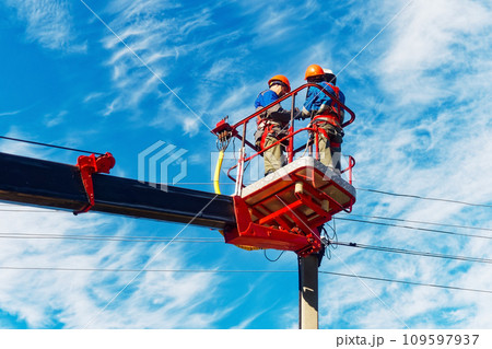 Two electricians from cradle of aerial platform or crane are repairing street lighting lamp 109597937