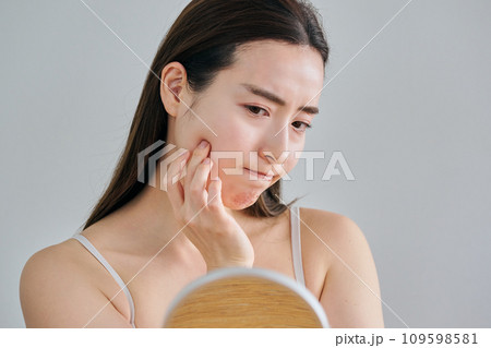 鏡を見ながら肌のシワを気にする30代女性 鏡を見ながら肌のシワを気にする30代女性 109598581