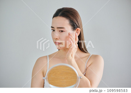 鏡を見ながら肌のシワを気にする30代女性 鏡を見ながら肌のシワを気にする30代女性 109598583