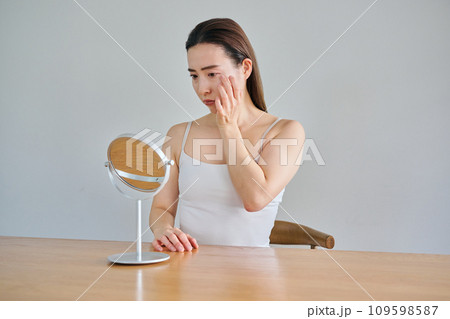 鏡を見ながら肌のシワを気にする30代女性 鏡を見ながら肌のシワを気にする30代女性 109598587