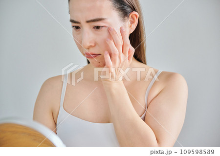 鏡を見ながら肌のシワを気にする30代女性 鏡を見ながら肌のシワを気にする30代女性 109598589
