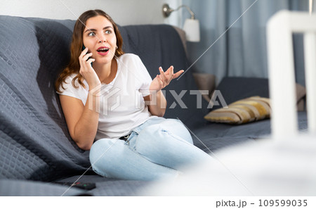 Cheerful woman talking on phone at home 109599035