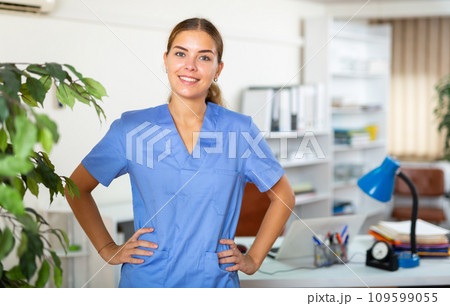 Confident young female doctor in blue uniform standing in office 109599055