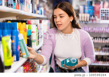 Young beautiful female shopper searching for mouthwashes Young beautiful female shopper searching for mouthwashes 109599164