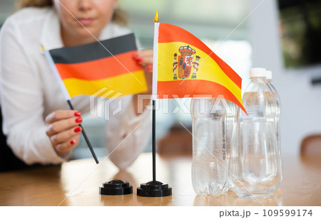 Young woman putting Germany and Spain flags on table in office 109599174