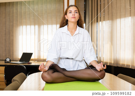 Portrait of a young girl doing yoga in a conference room 109599182