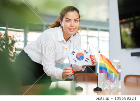 Young woman putting South Korea and LGBT flags on table in office Young woman putting South Korea and LGBT flags on table in office 109599221