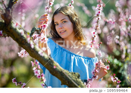 Woman in blue dress posing in blossom spring garden Woman in blue dress posing in blossom spring garden 109599464